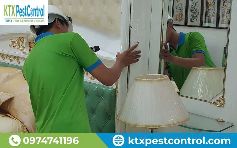 Kỹ thuật viên KTX kiểm tra và xử lý mối tại khu vực tủ gỗ trong nhà.